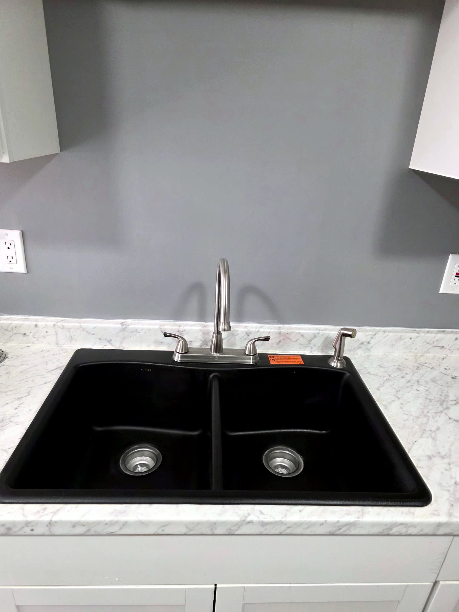 Black double-basin kitchen sink in a light stone counter.