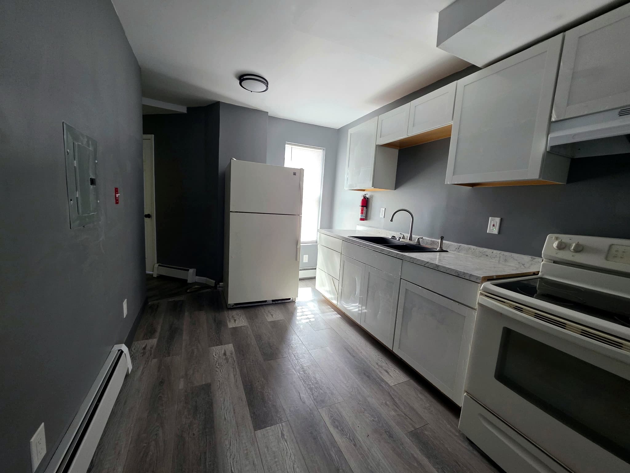 Kitchen with white cabinets, a refrigerator, a black sink, and a white range.