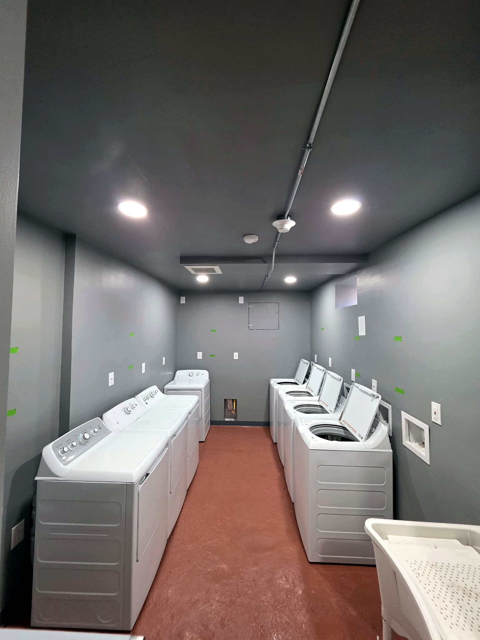 Laundry room with rows of white washers and dryers.